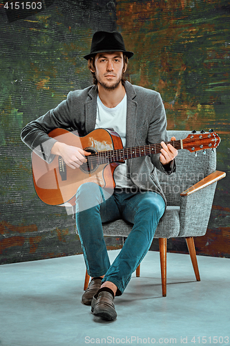 Image of Cool guy with hat playing guitar on gray background