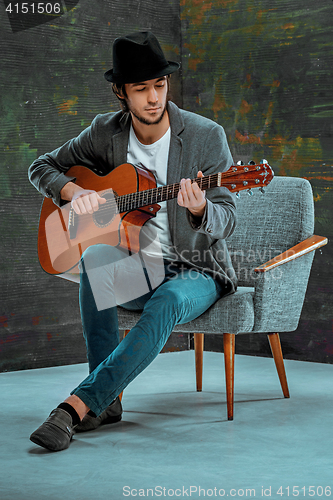 Image of Cool guy with hat playing guitar on gray background