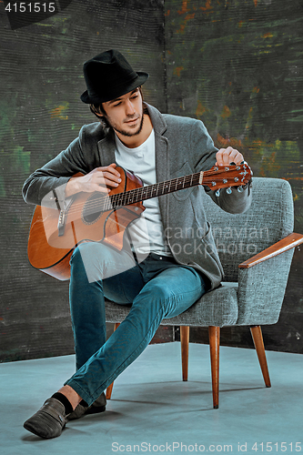 Image of Cool guy with hat playing guitar on gray background