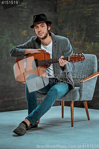 Image of Cool guy with hat playing guitar on gray background