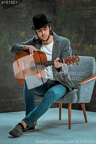 Image of Cool guy with hat playing guitar on gray background