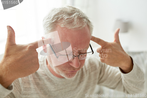 Image of senior man suffering from headache at home