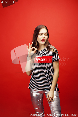 Image of young pretty emitonal posing teenage girl on bright red background, happy smiling lifestyle people concept