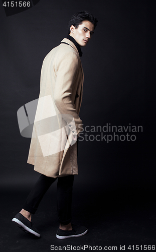 Image of cool real young man in coat on black background posing