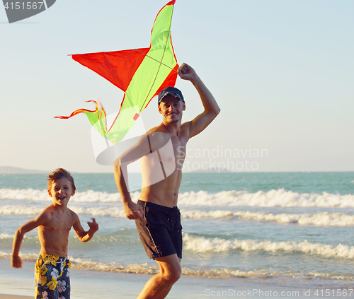 Image of father with son, sunset at the seacoast playing kite, happy family 