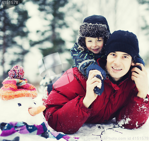 Image of portrait of happy father with his son outside with snowman close