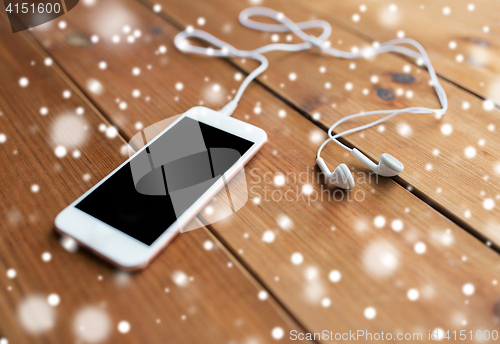 Image of close up of blank smartphone and earphones on wood