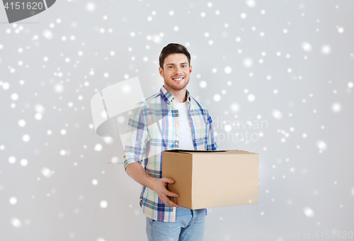 Image of smiling young man with cardboard box at home