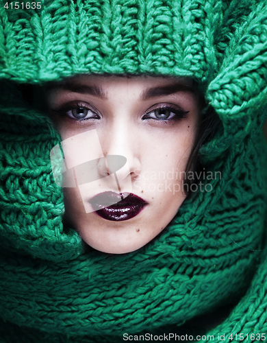 Image of young pretty woman in sweater and scarf all over her face close 