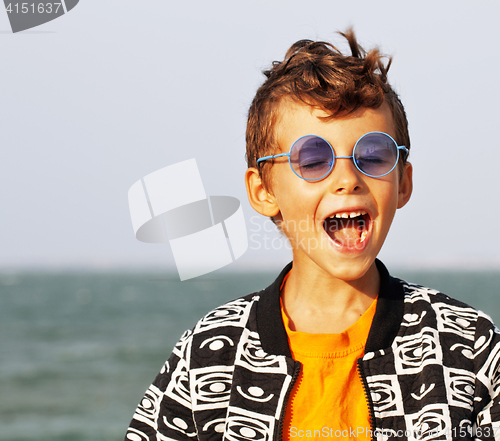 Image of cute little boy at seacoast in fashion clothers and blue glasses