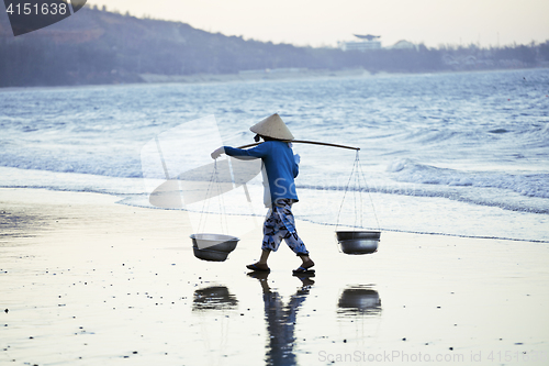 Image of vietnam woman in vietnamese hat walking on seacost at sunset