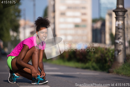 Image of African american woman runner tightening shoe lace