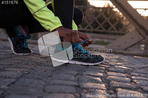 Image of African american woman runner tightening shoe lace