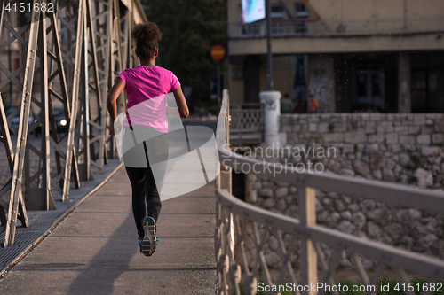 Image of african american woman running across the bridge