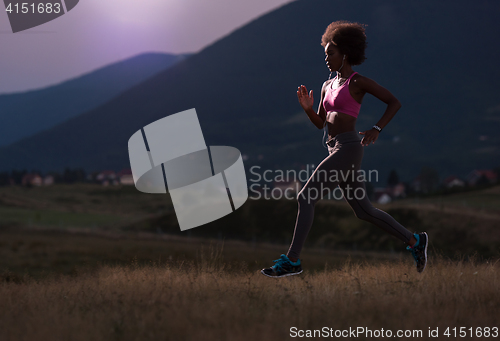 Image of Young African american woman jogging in nature