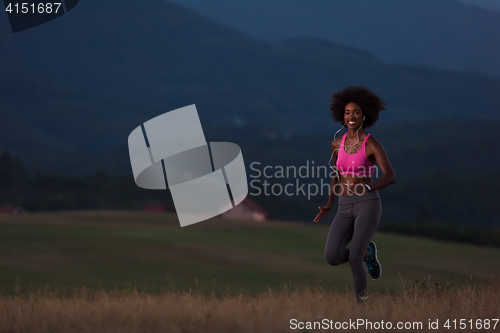 Image of Young African american woman jogging in nature