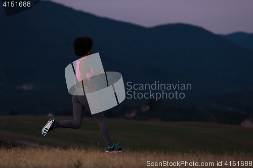 Image of Young African american woman jogging in nature