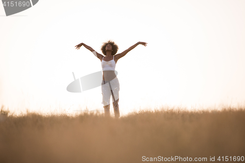 Image of young black girl dances outdoors in a meadow