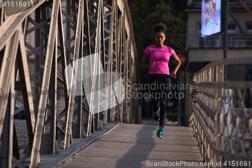 Image of african american woman running across the bridge