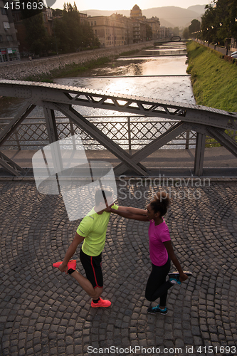 Image of jogging couple warming up and stretching in the city