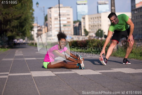 Image of jogging couple warming up and stretching in the city