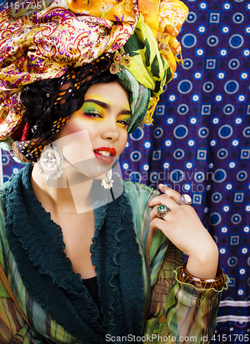 Image of beauty bright woman with creative make up, many shawls on head l