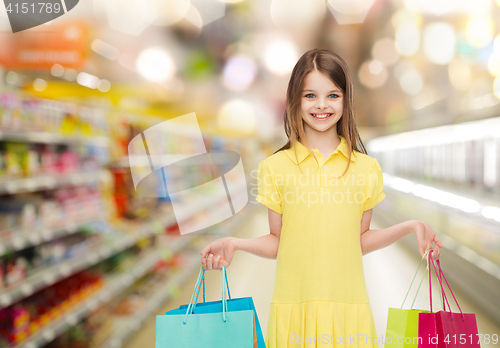 Image of smiling girl with shopping bags over supermarket