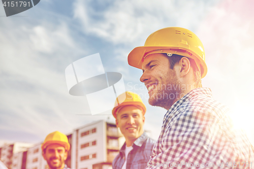 Image of group of smiling builders in hardhats outdoors