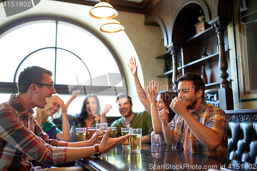 Image of friends with beer watching football at bar or pub