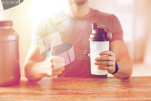 Image of man with protein shake bottle showing thumbs up