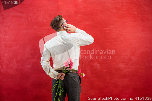 Image of Man holding bouquet of carnations behind back