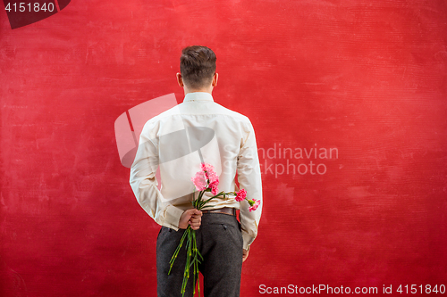 Image of Man holding bouquet of carnations behind back