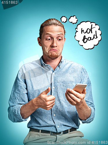 Image of The young surprised caucasian businessman on blue background talking by cell phone