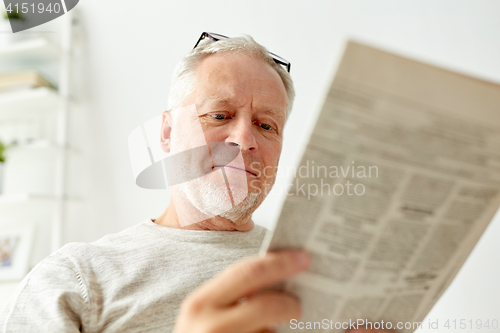 Image of close up of senior man reading newspaper at home