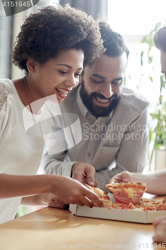Image of happy business team eating pizza in office