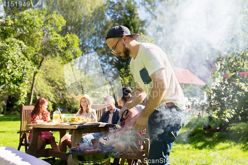 Image of man cooking meat on barbecue grill at summer party
