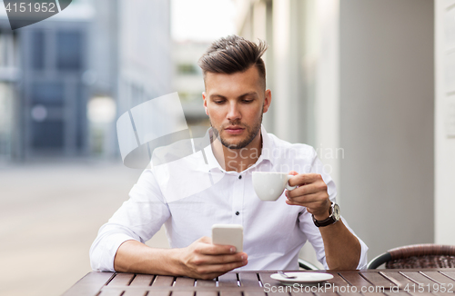 Image of man with smartphone drinking coffee at city cafe