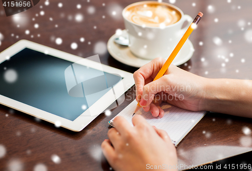 Image of woman with tablet pc writing to notebook