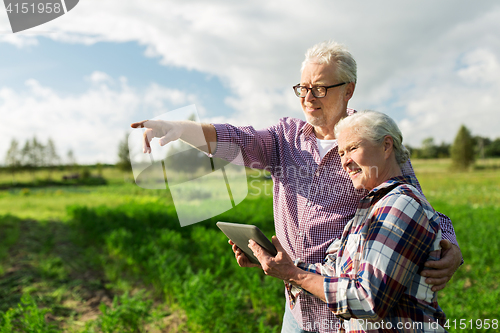 Image of happy senior couple with tablet pc at summer farm