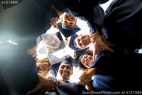 Image of happy students or bachelors in mortar boards