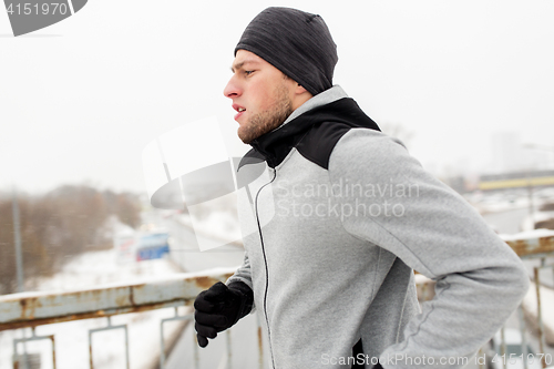 Image of man running along winter bridge