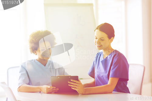 Image of happy doctors with tablet pc meeting at hospital