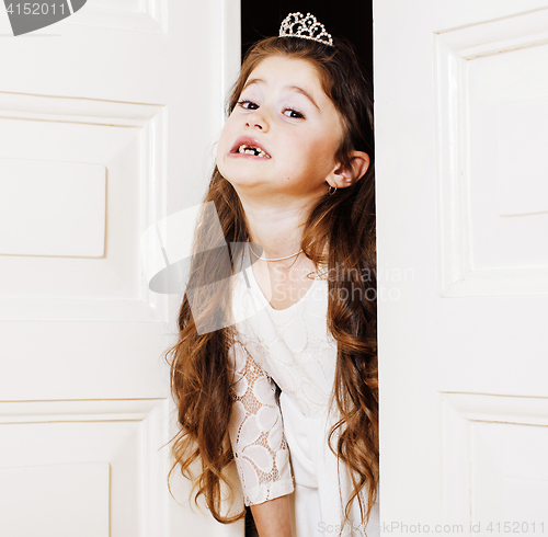 Image of little cute girl at home, opening door well-dressed in white dre