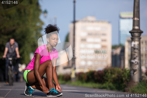 Image of African american woman runner tightening shoe lace