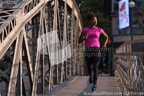 Image of african american woman running across the bridge