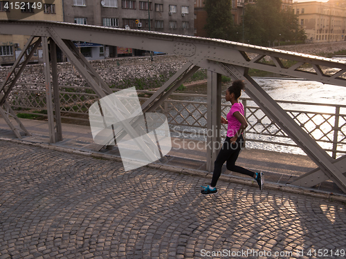 Image of african american woman running across the bridge