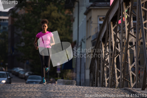 Image of african american woman running across the bridge