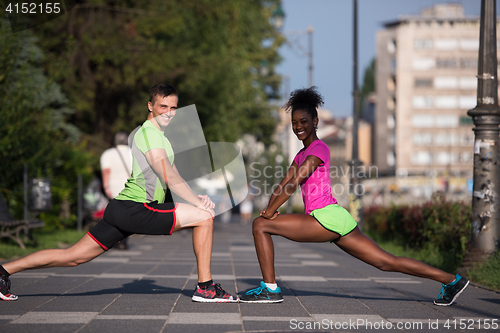 Image of jogging couple warming up and stretching in the city