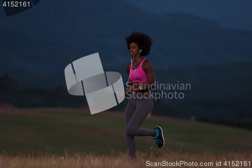 Image of Young African american woman jogging in nature