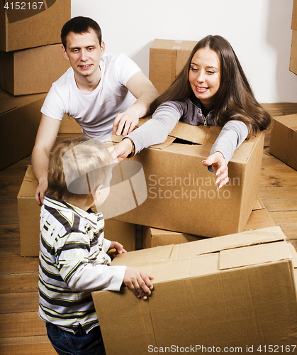 Image of happy smiling family in new house playing with boxes little cute kid, lifestyle people concept